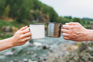 Couple of travelers holding mugs featuring woman, man, and tea