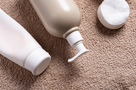 Plastic bottle with dispenser for massage oil on brown towel