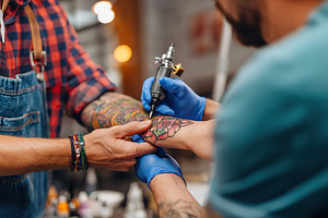Tattoo artist inking a detailed floral design on a client's forearm in a bustli, an Arts & Entertainment Photo by AlyaAnd