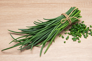 Fresh chives tied with twine on wooden table with chopped chives, a Food & Drink Photo by Olena Rudo