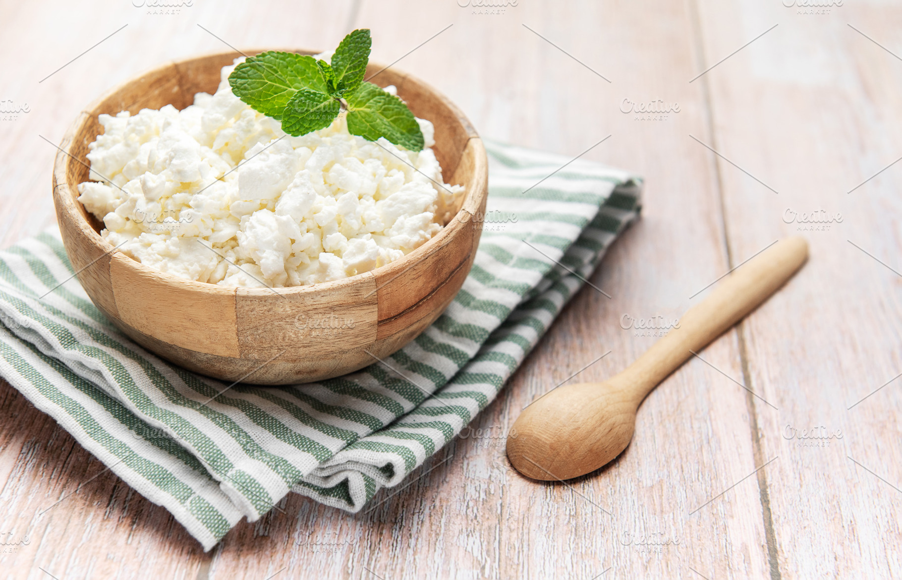 Cottage cheese in wooden bowl with mint on rustic table, a Food & Drink Photo by Olena Rudo