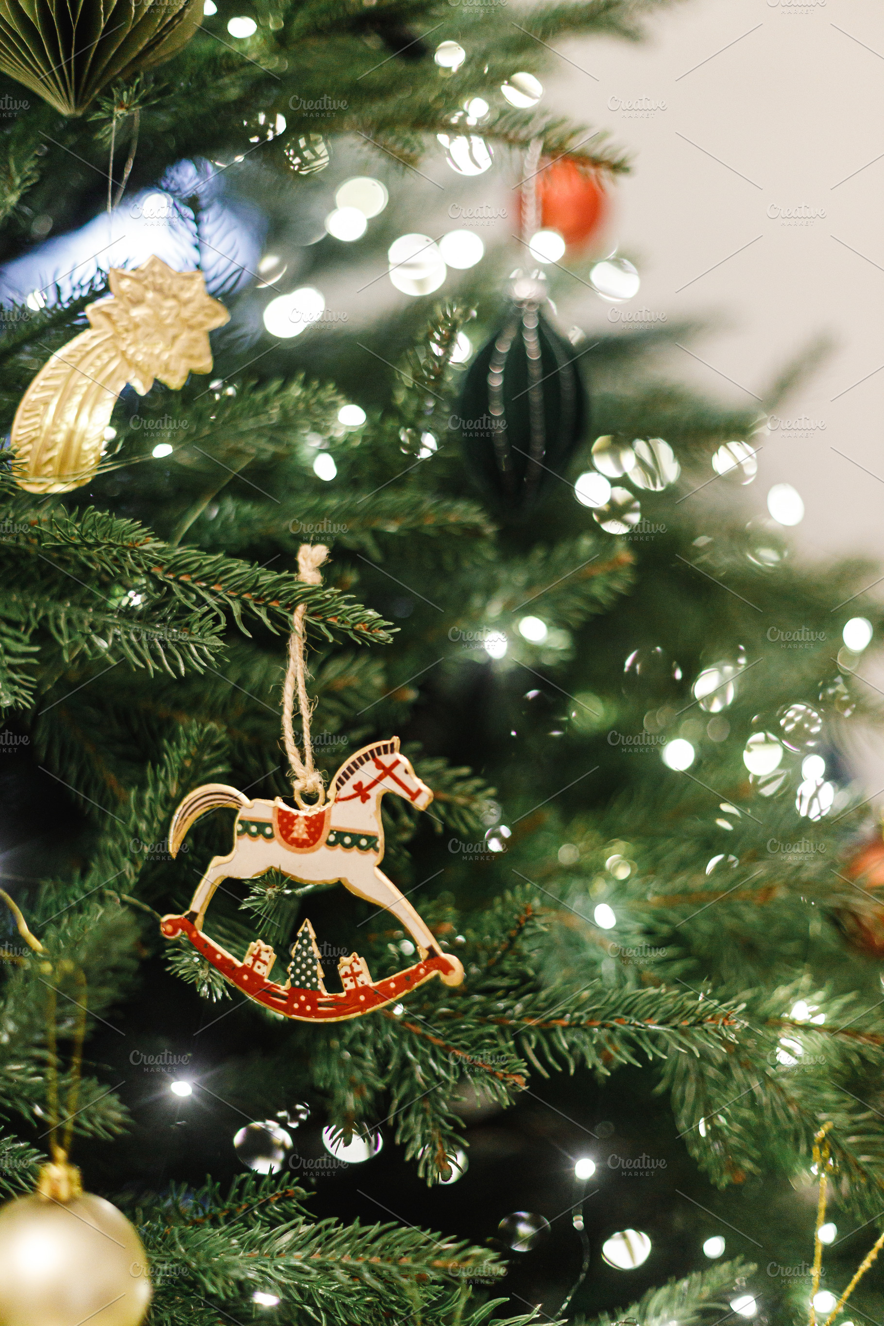 Horse christmas toy hanging on tree branch with festive lights., a Holiday Photo by Sonjachni