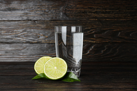 Glass of water, lime and leaves on wooden background, a Food & Drink Photo by AtlasStudio PRO