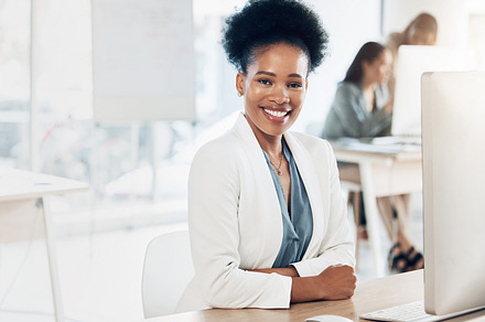 Leadership, happy and portrait of a businesswoman in the office with a computer working on a project. Happiness, smile and African female corporate manager sitting at her desk with a pc in workplace., a Photo by Peopleimages.com