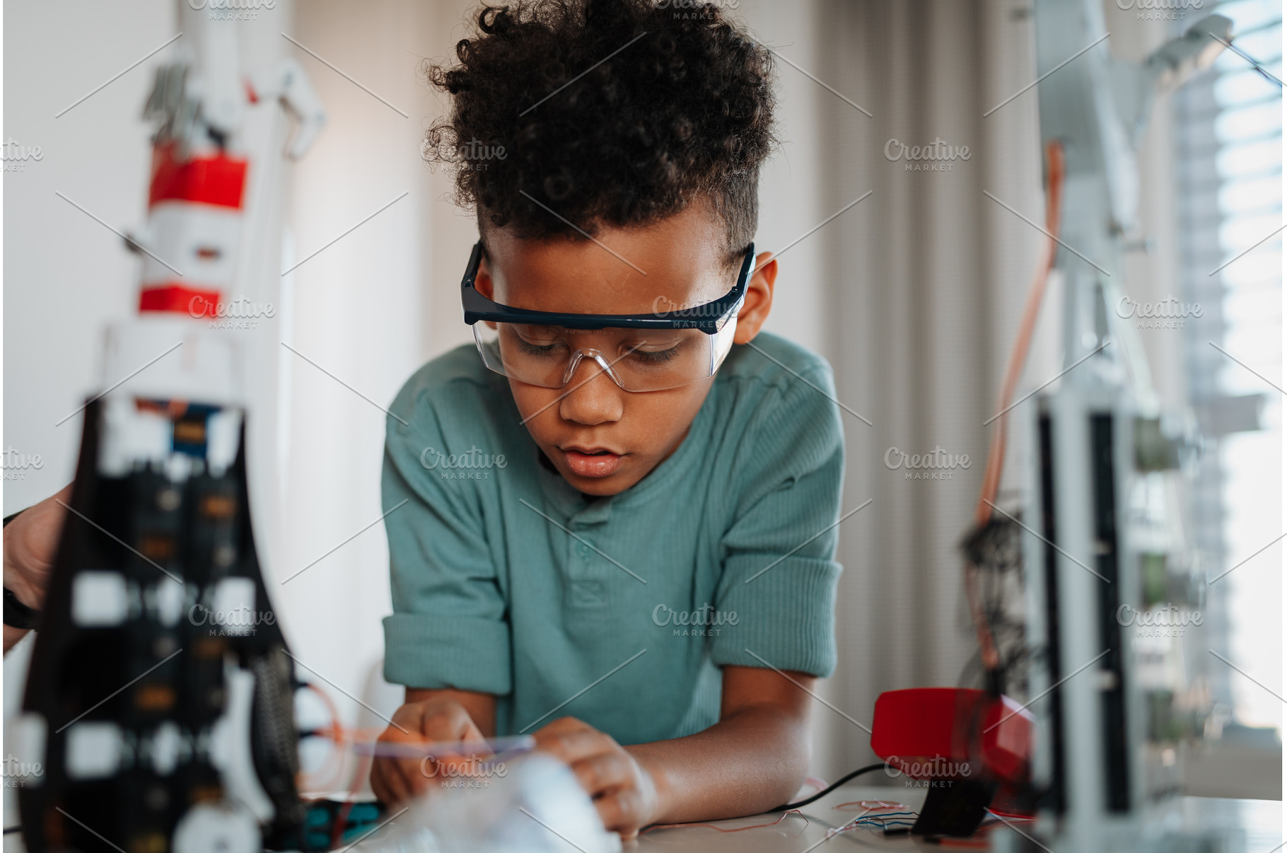 Focused boy working on small robot, a School & Education Photo by HalfPoint