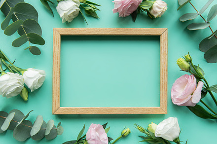 A wooden frame surrounded by white and pink roses on a mint gree, a Nature Photo by Olena Rudo