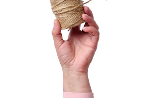A woman's hand in a pink sleeve holds a jute rope in a skein on, a Person Photo by ndanko