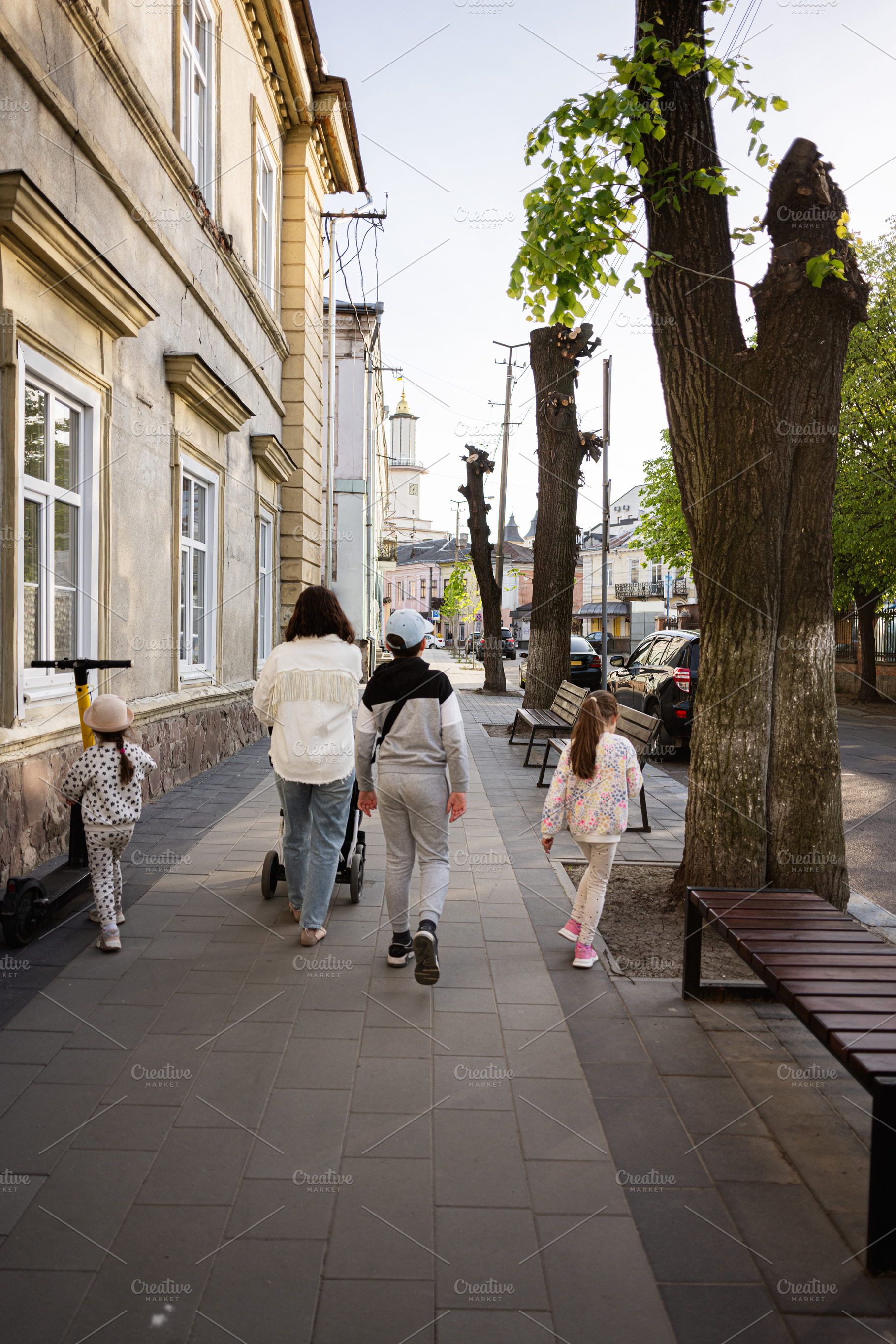 A family strolling on a sunny path with charming urban scenery and trees, a Person Photo by AS photostudio