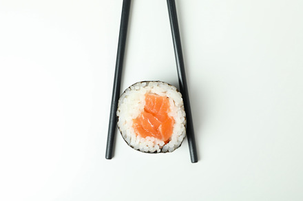 Chopsticks with maki on white background, close up, a Food & Drink Photo by AtlasStudio PRO