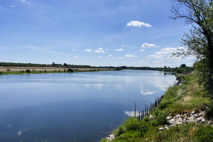 Beautiful riverside landscape on a clear day with blue sky and greenery, a Photo by AS photostudio