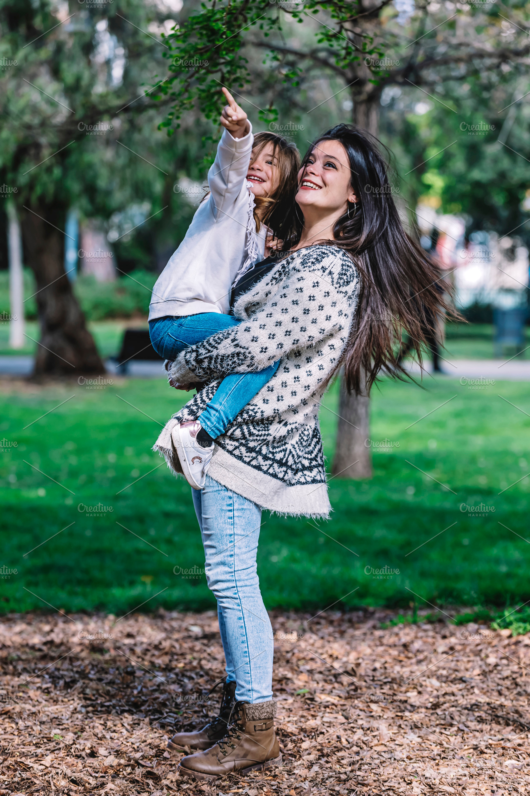 Mother holding her daughter and playing around park on beautiful morning., a Person Photo by 2Design