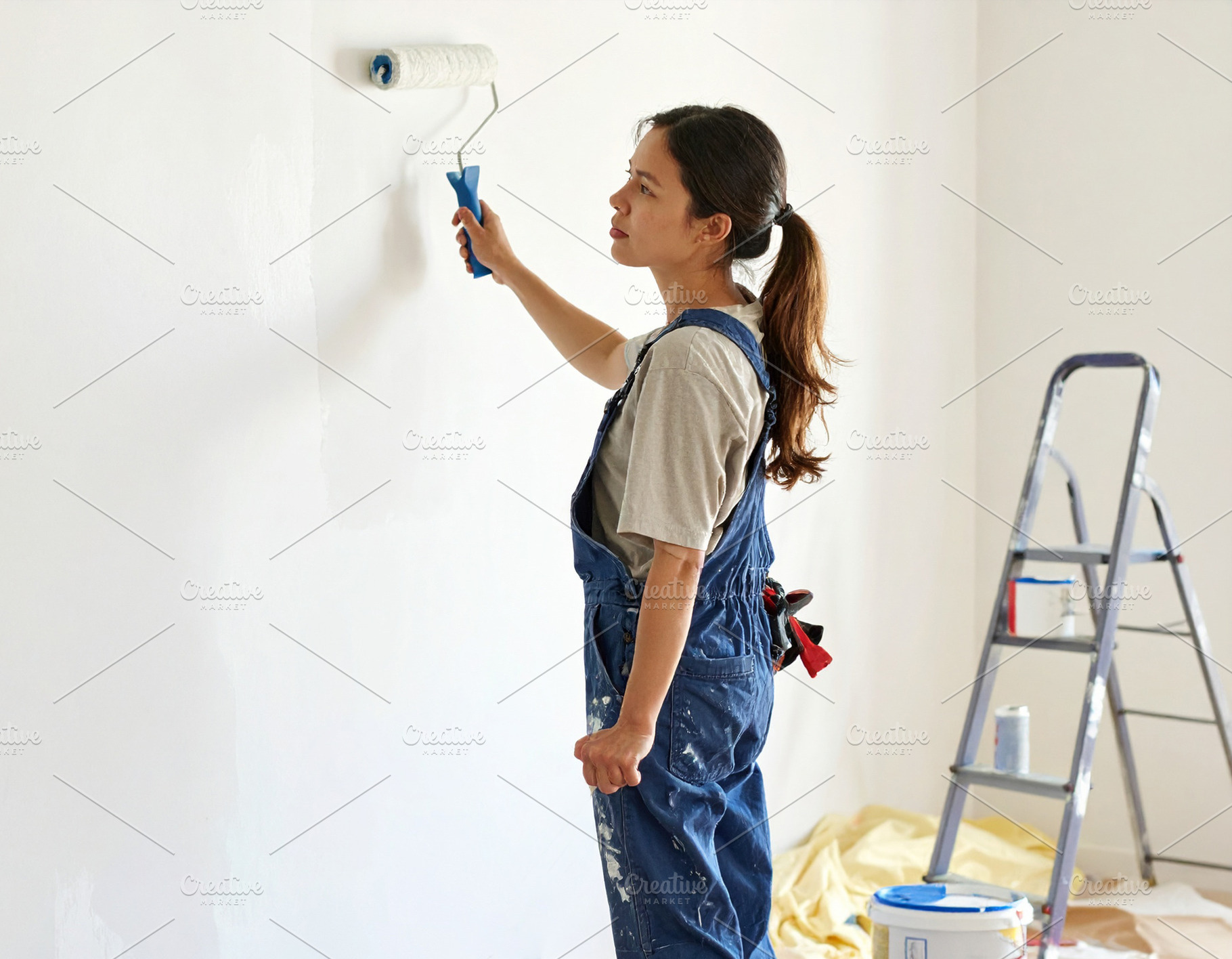 House painter working indoors, painting a wall with a roller, a Person Photo by DanFLCreativo