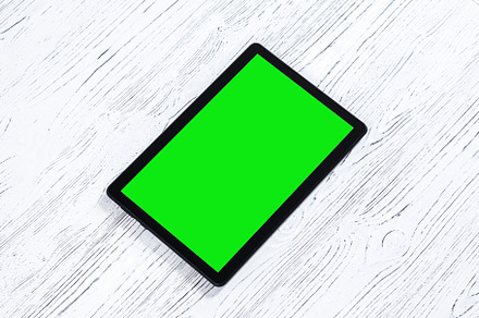 Black tablet with green screen on a wooden table mock up. Copy s, an Abstract Photo by Eugene_Photo