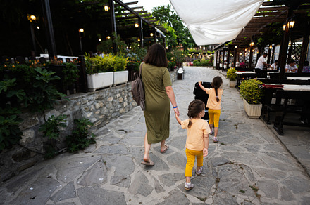 Back view of mother and daughters walking in the terrace of old, a Person Photo by AS photostudio