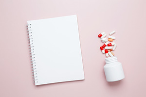 White bottle container with colorful medication capsules and blank notebook. Co, a Photo by matucha