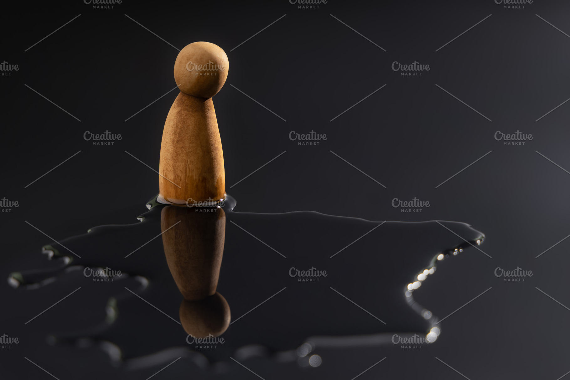 A wooden peg doll stands alone, staring down at its reflection i, a Photo by salmon.black