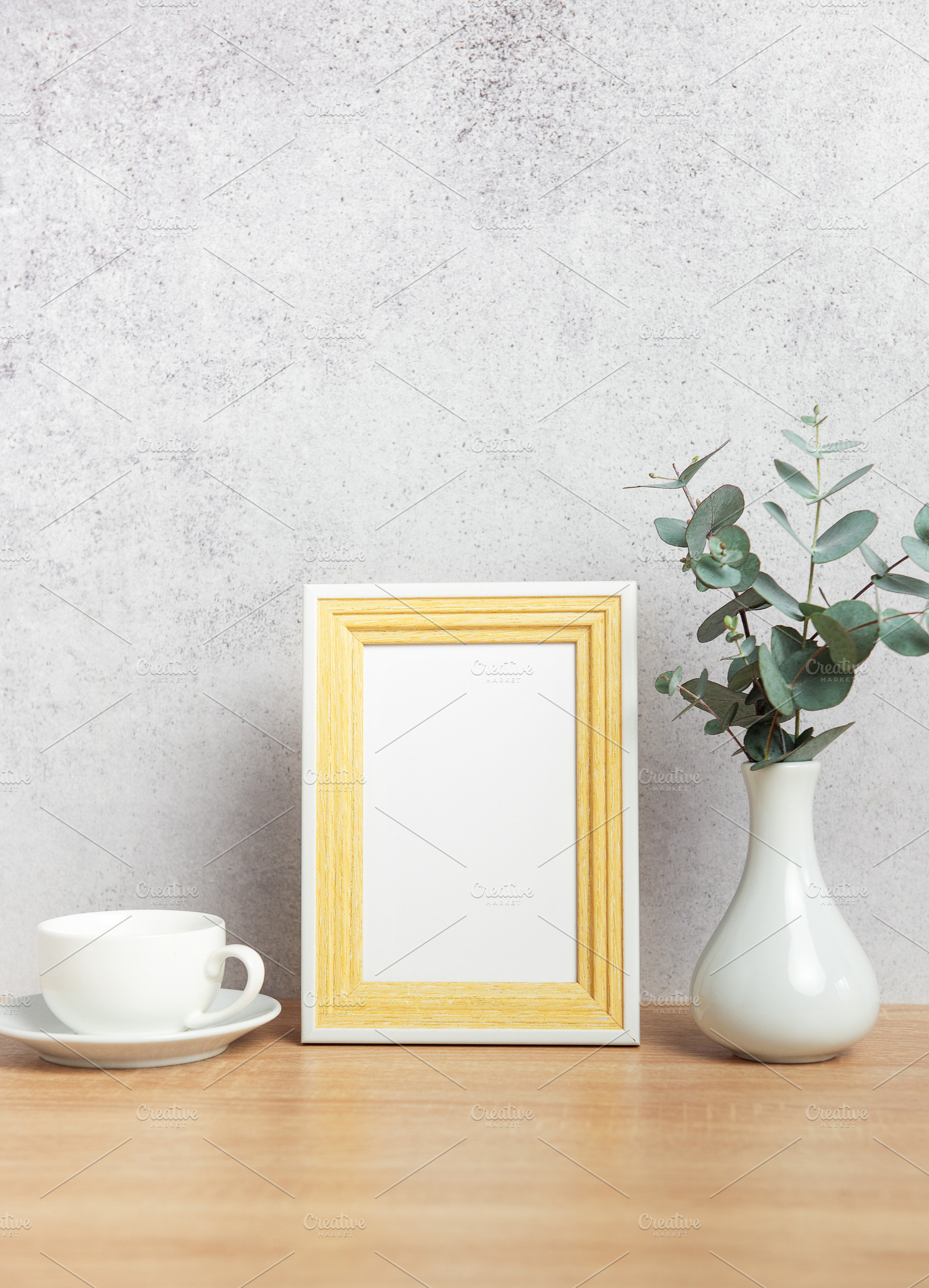 Empty photo frame, coffee cup and eucalyptus branches on table, a Business Photo by Olena Rudo