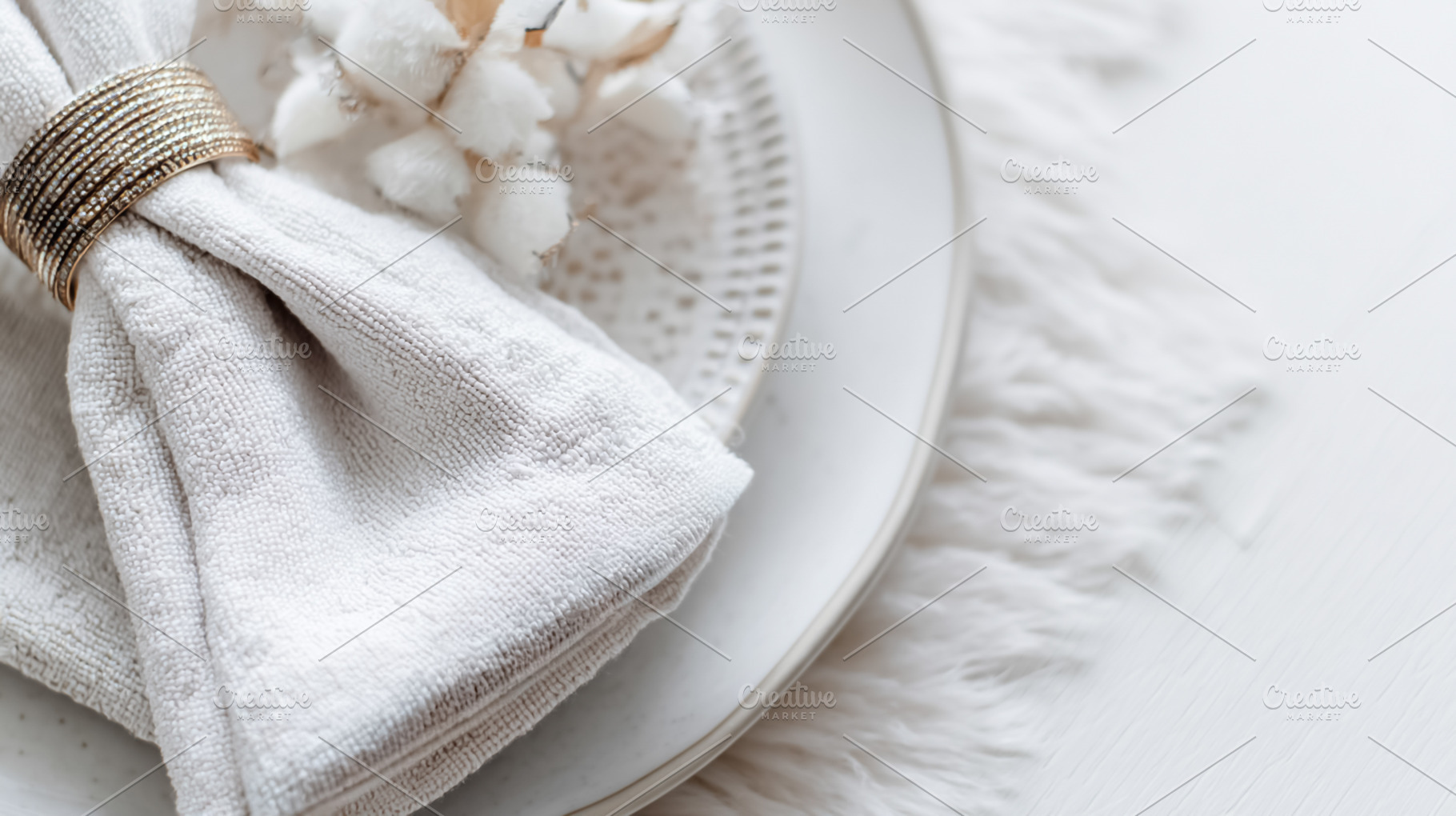 Elegant table setting with a gold napkin ring and cotton branch, a Photo by Studio ANNA