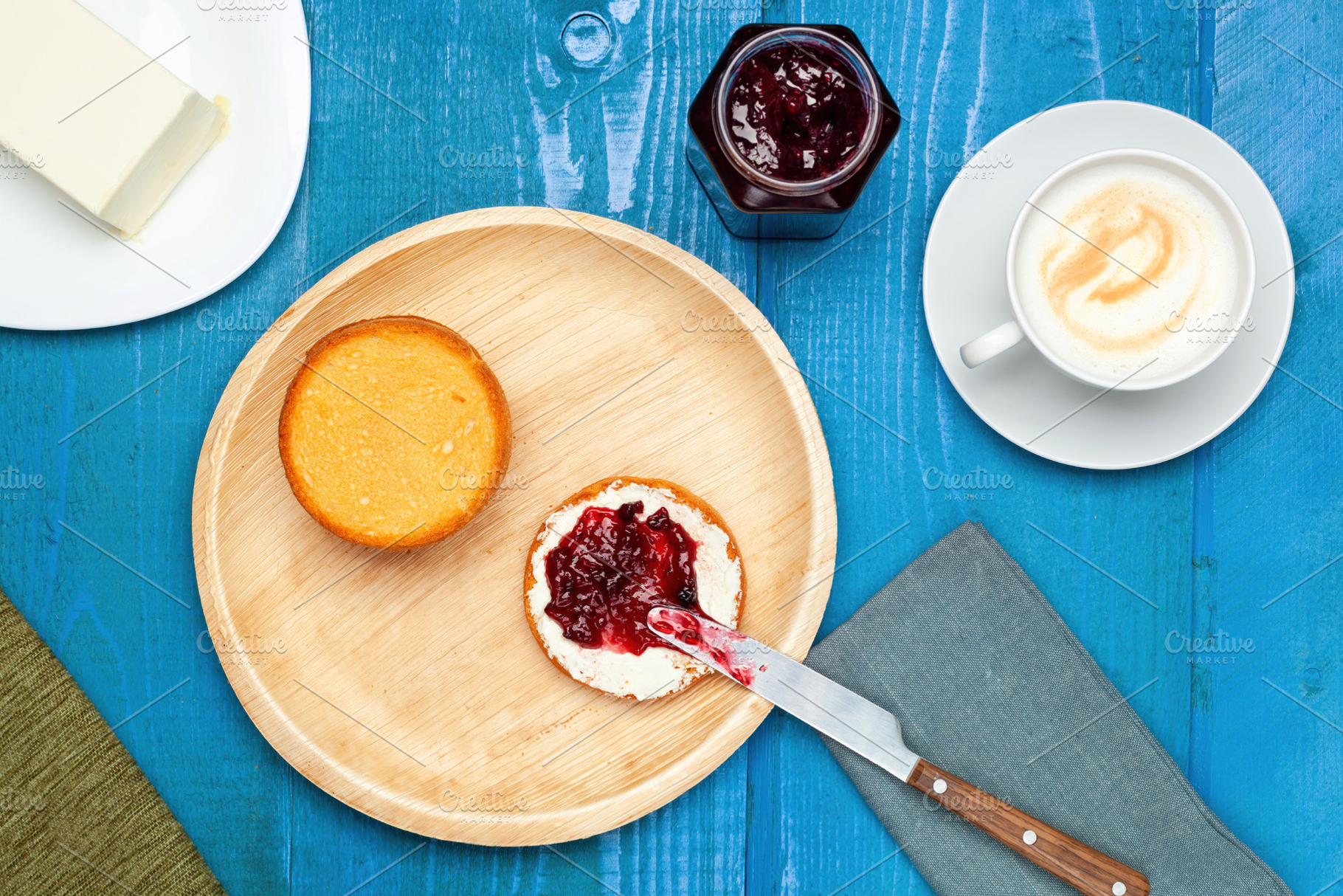 Preparing a delicious breakfast with rusks, butter, jam and cappuccino on a blu, a Food & Drink Photo by Antonio Gravante Market
