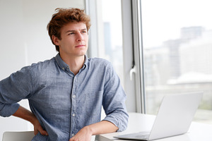 Man with back pain working on laptop at home office, a Person Photo by AlyaAnd