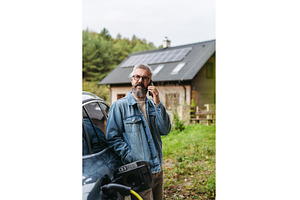 Man charging electric car in front, a Transportation Photo by HalfPoint