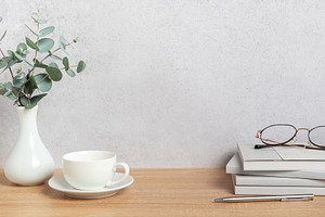 Eucalyptus branches, coffee cup, books and eyeglasses resting on, a Background Photo by Olena Rudo