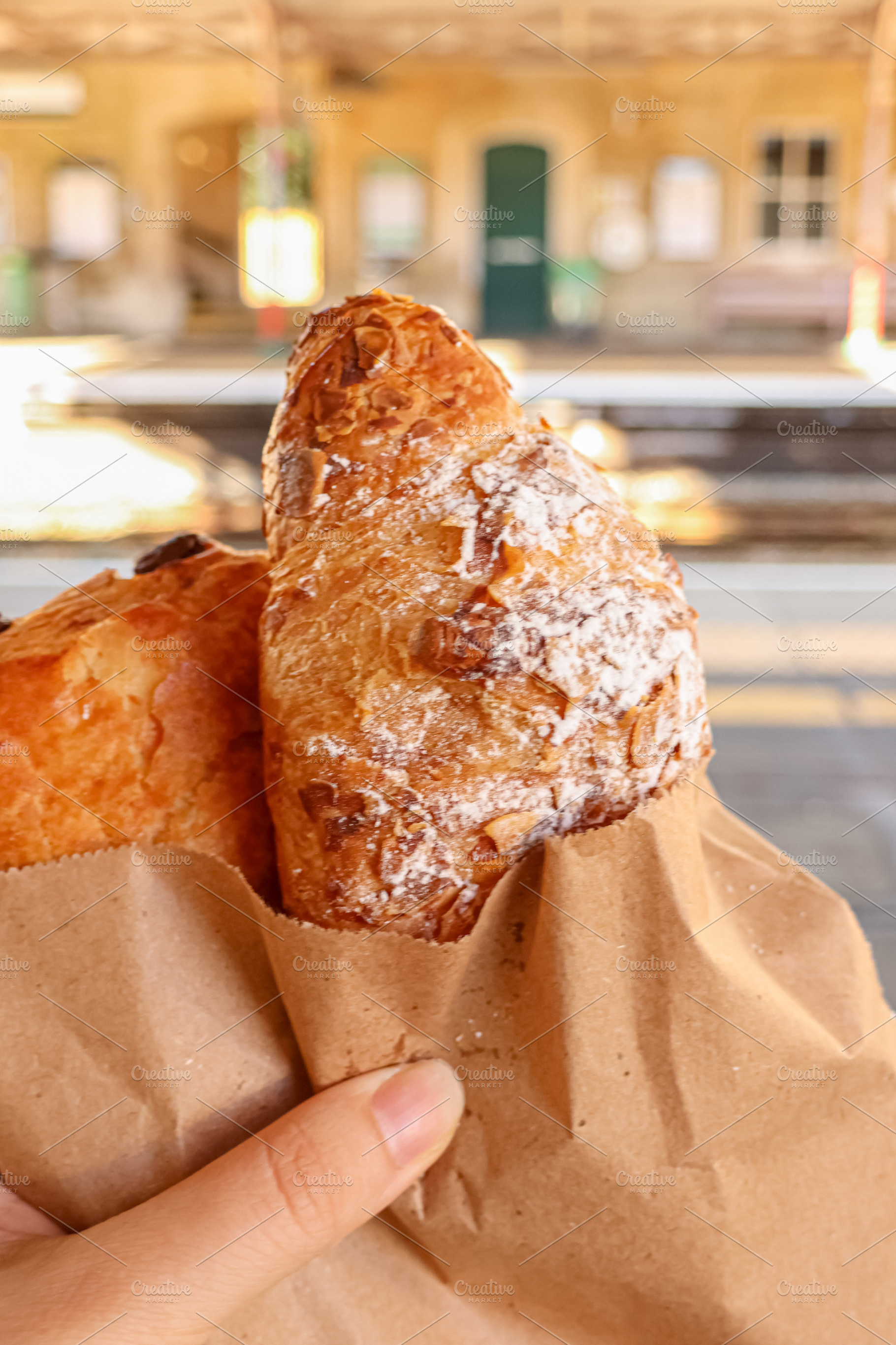 Croissant and pastry in paper bag, holding fresh baked food at train station, e, a Photo by Studio ANNA