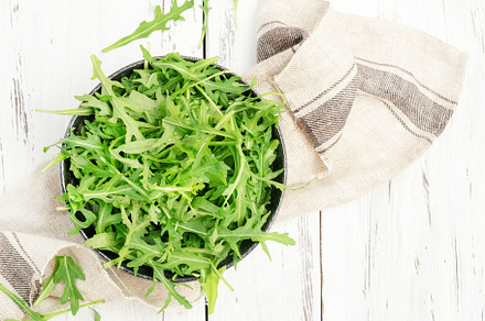 Fresh green arugula in rustic ceramic bowl on white kitchen tabl, a Food & Drink Photo by 5PH