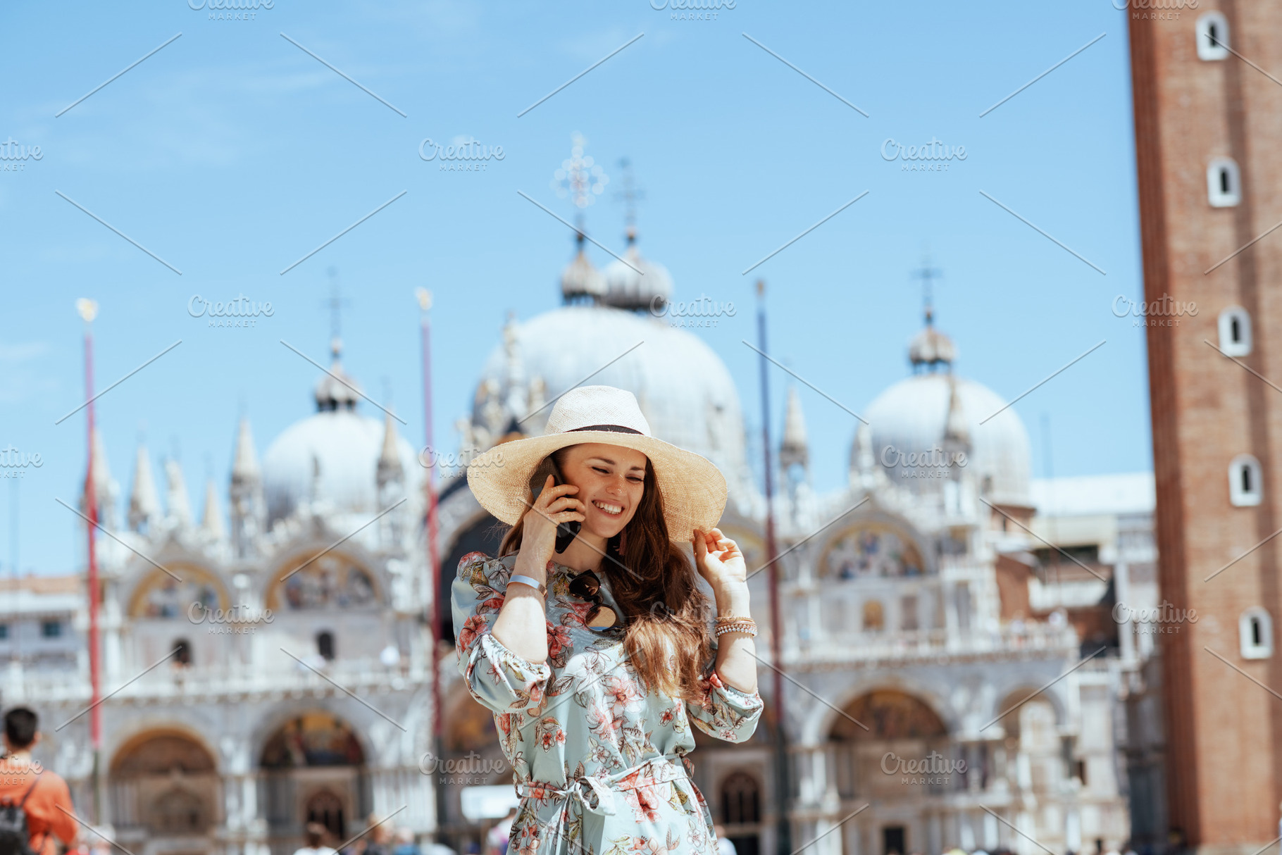 smiling traveller woman in floral dress using smartphone, a Person Photo by Alliance Images