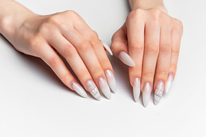 Woman's hands showing long white almond shape nails with art, a Photo by Olena Rudo