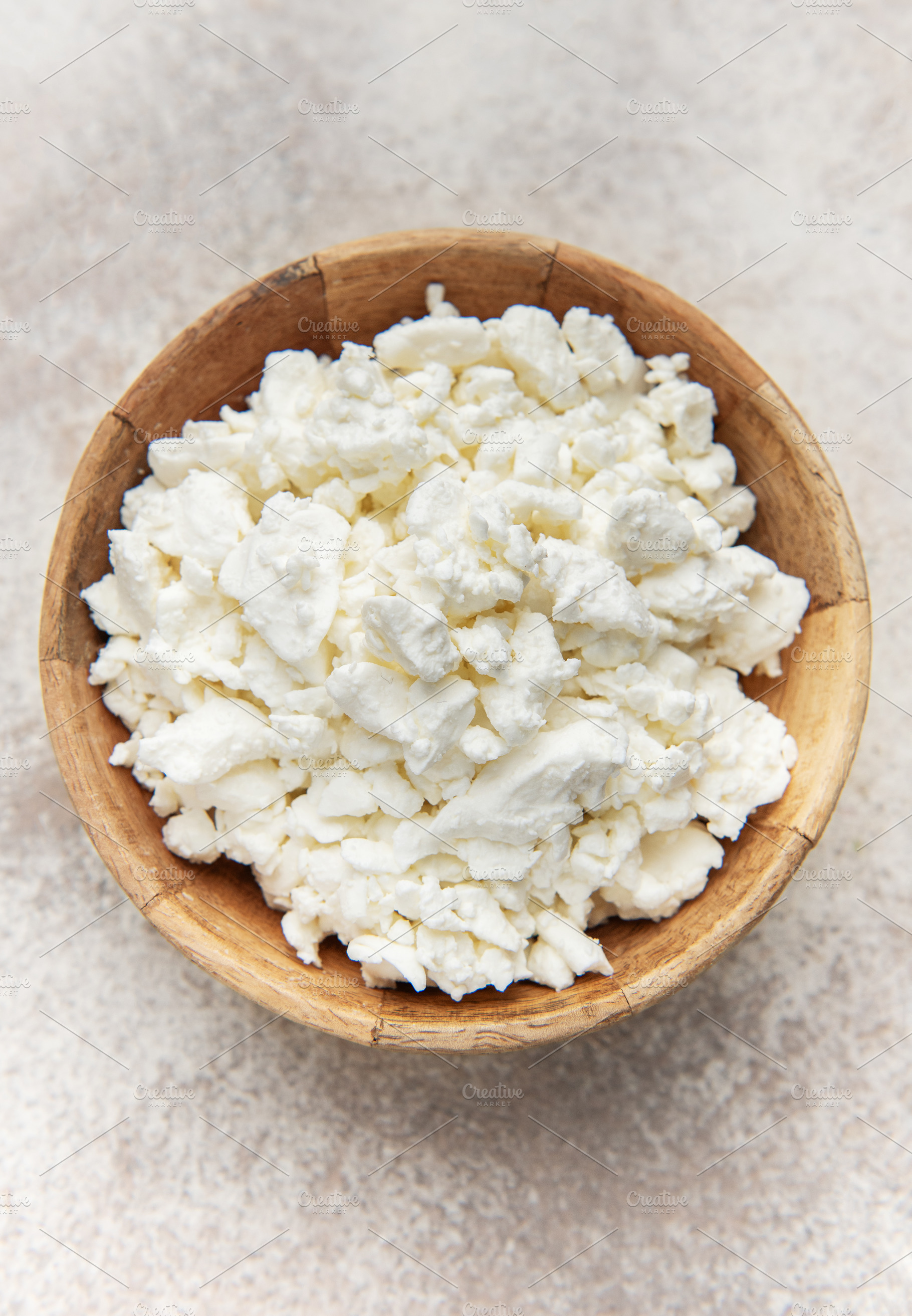 Cottage cheese in wooden bowl on rustic background, a Food & Drink Photo by Olena Rudo