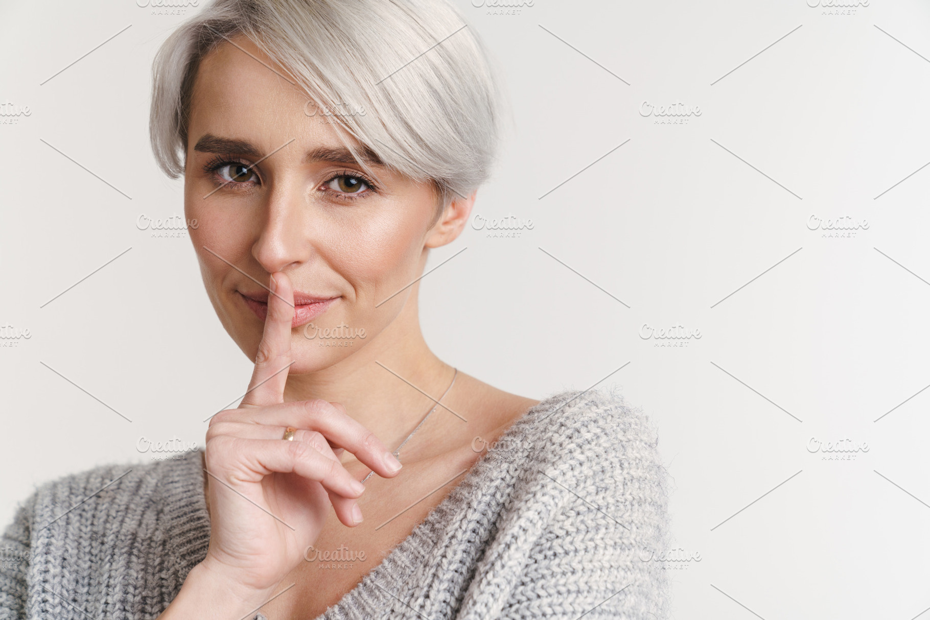 Pleased beautiful silver girl showing silence gesture, a Background Photo by Dean Drobot