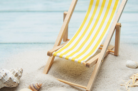 Miniature deck chair on sandy beach with seashells inviting rela