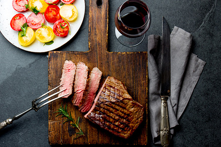 Sliced grilled medium rare beef steak served on wooden board barbecue bbq, a Food & Drink Photo by LARISA BLINOVA