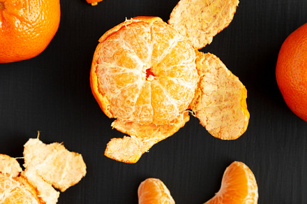 Raw Organic Mandarin Oranges on a black surface, top view. Flat, a Food & Drink Photo by LiudmylaChuhunova