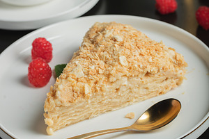 Sliced Napoleon cake on a white wooden table. Classic dessert, a Food & Drink Photo by Budarinphoto
