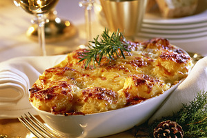 Potato gratin with rosemary sprig ready for a holiday dinner, featuring wine gl, a Photo by Studio ANNA