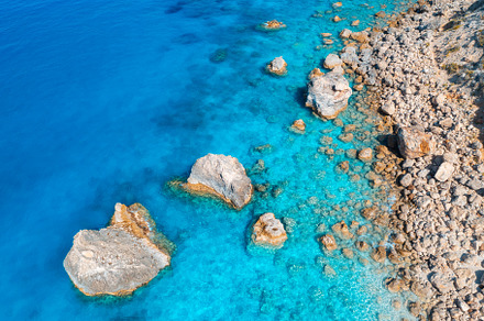 Aerial view of clear blue sea, stones and rocks in water, a Nature Photo by den-belitsky