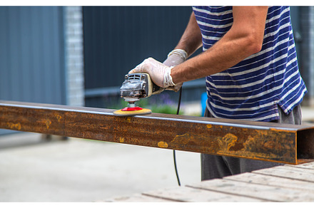 A man processes a metal pole, an Industrial Photo by yanadjana