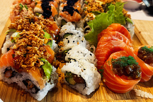 Assorted sushi rolls and fresh sashimi served on a wooden platter in a restaura, a Photo by AS photostudio