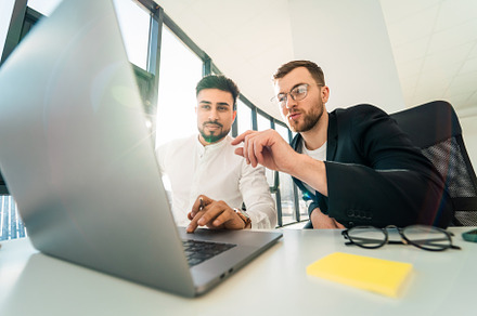Two handsome business men use laptop, a Photo by borodai94