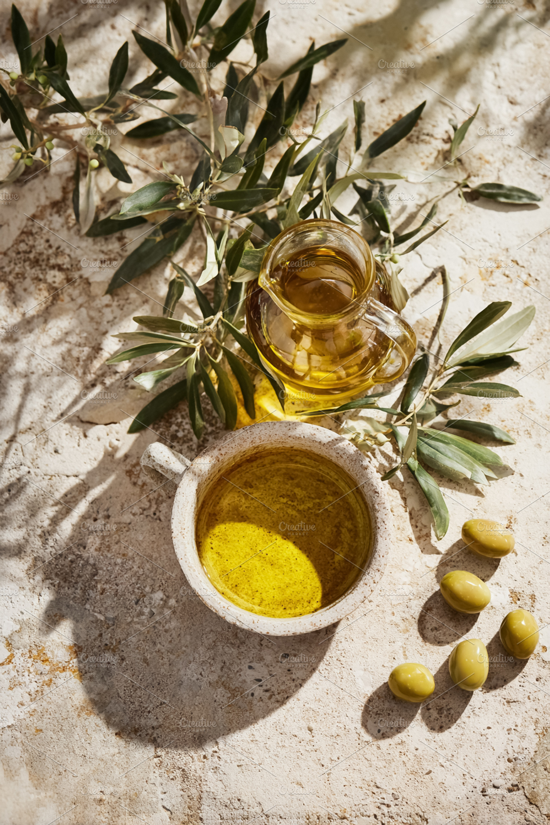 Olive oil in ceramic bowl and glass pitcher with green olives an, a Photo by Studio ANNA