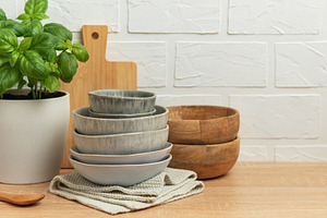 Kitchen table setting featuring stacked bowls, fresh basil, and, a Food & Drink Photo by Olena Rudo