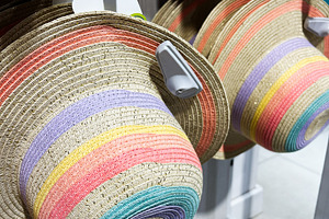 Colorful wide brim hats hung on a display rack in a retail store, a Photo by AS photostudio