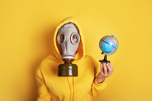 Individual wearing a gas mask and yellow hoodie holds a small gl, a Person Photo by Ales Munt