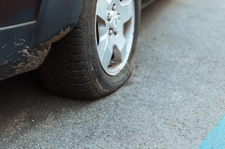 Closeup on car with flat tire in city, a Transportation Photo by Alliance Images