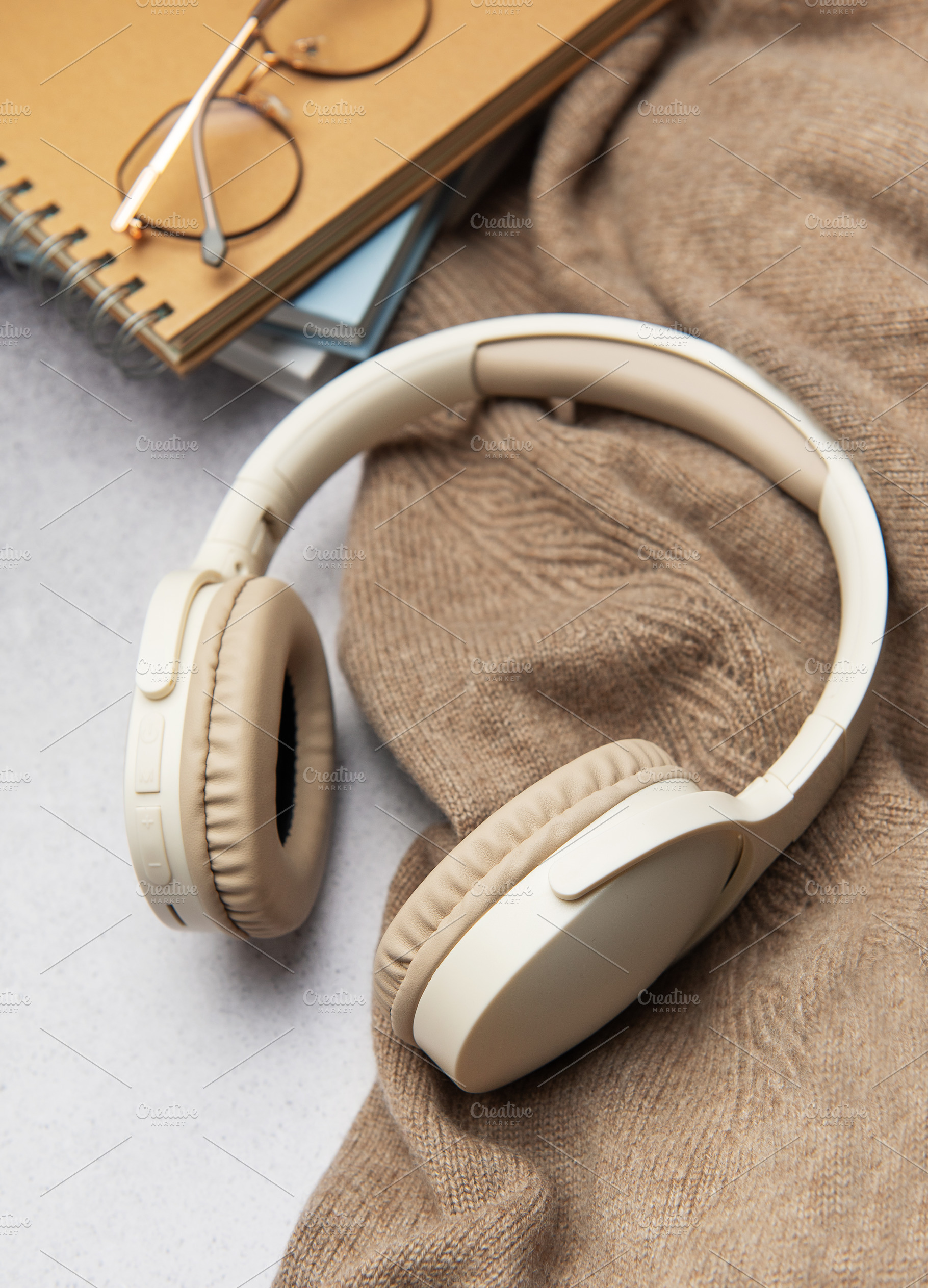 Wireless headphones, eyeglasses and notebooks resting on cozy sw, a Technology Photo by Olena Rudo