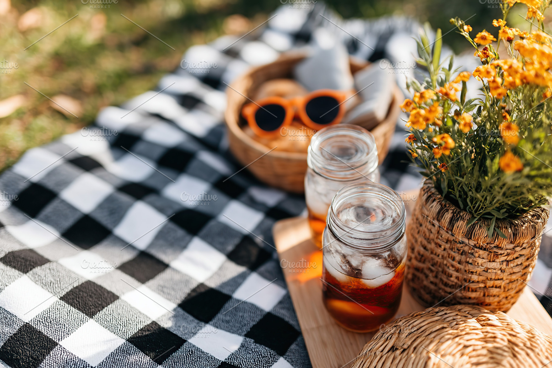 Picnic setup with refreshing drinks and flowers in a city park on a sunny day, a Photo by AlyaAnd