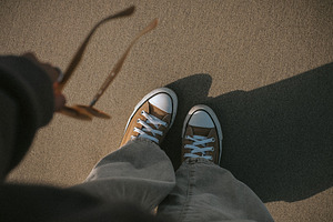 Female feet in sneakers on sand