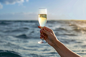 Arm raising a champagne glass from the middle of the sea, a Food & Drink Photo by DanFLCreativo